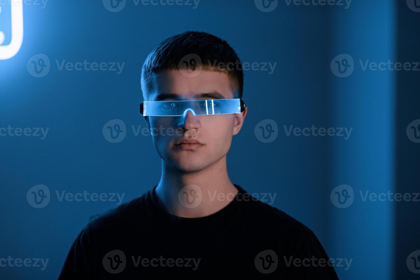 Young man in a neon room with futuristic glasses. photo