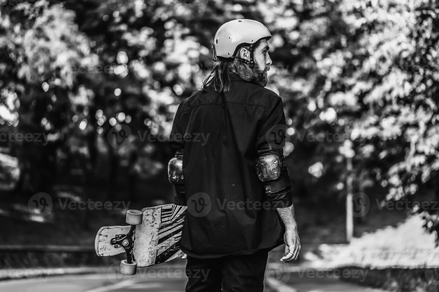 Black and white portrait of a bearded guy holding a skateboard, longboard. photo