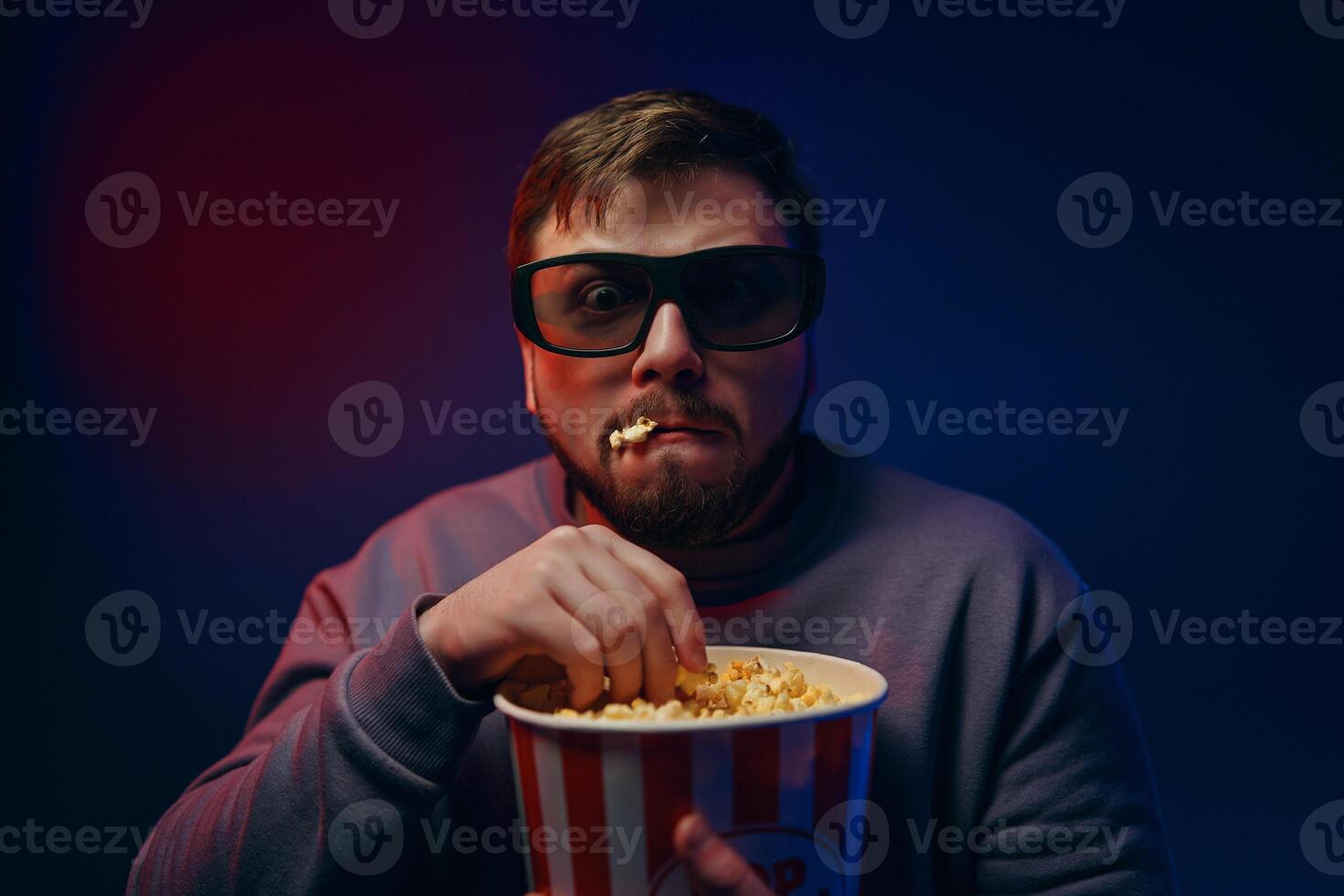 A man is watching a scary movie. Watching a movie with popcorn. photo
