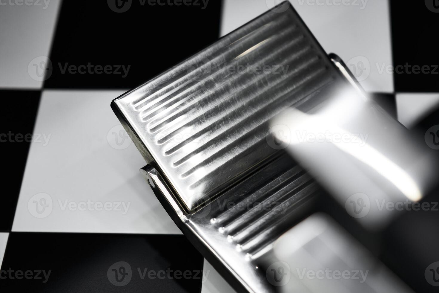 Close-up view of a chrome foot pedal on a checkerboard surface in a workshop photo