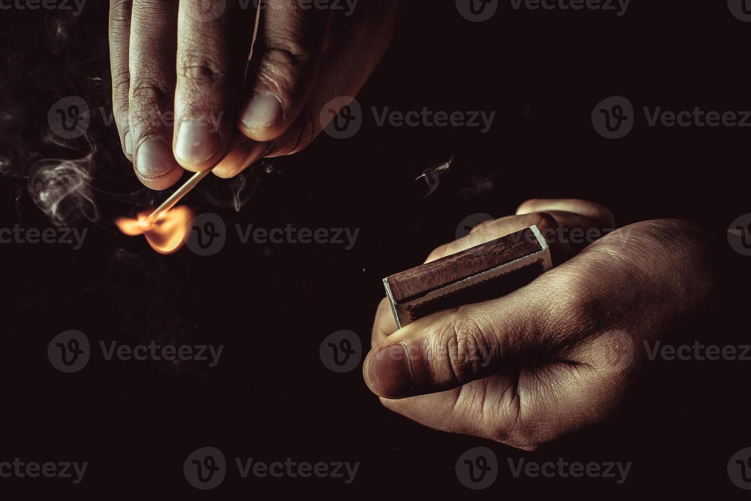 Playing with fire. A burning match in a man's hand on a black background. photo