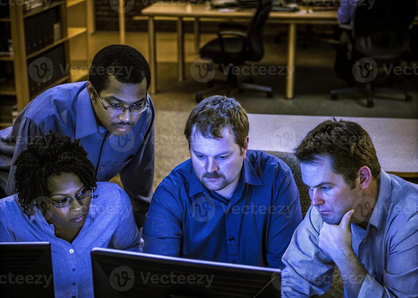 three men and a woman looking at a computer screen photo