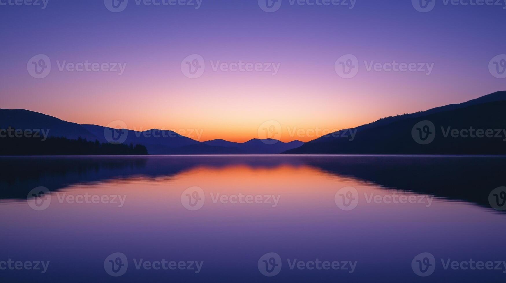 As the day ends, the sky is painted in vibrant hues of orange and purple, casting a serene glow over the tranquil lake and surrounding mountains photo