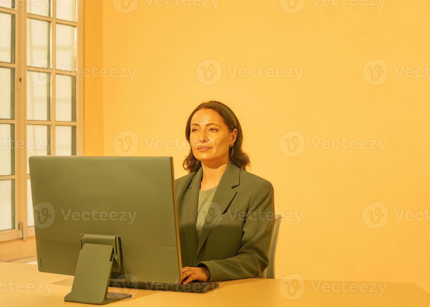 a woman in a suit sitting at a desk with a computer photo