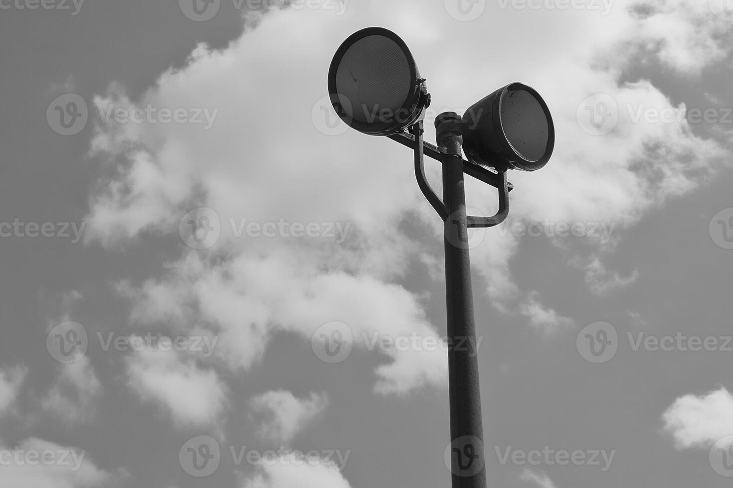A black and white image of a streetlight against clouds. photo