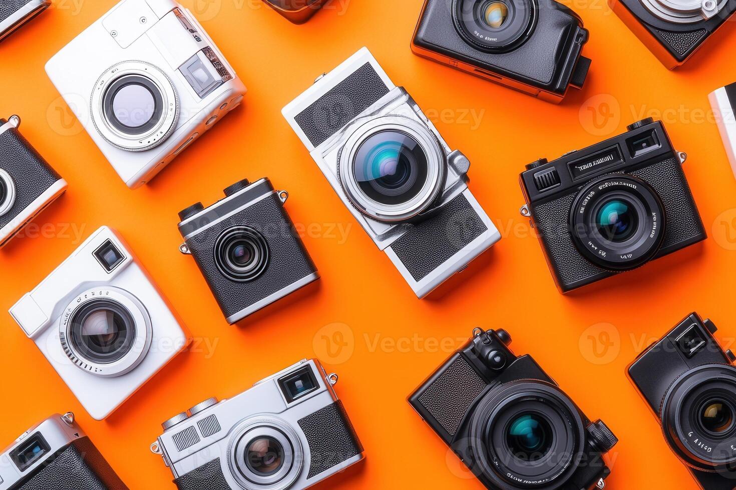 A collection of various cameras on an orange background. photo