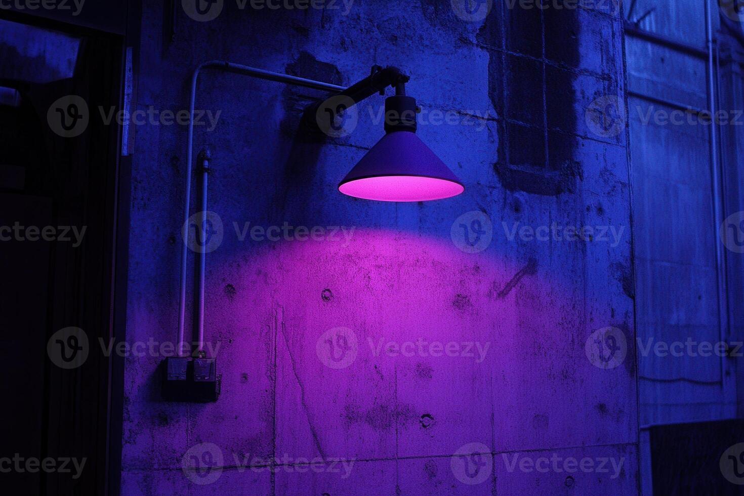 A purple-lit industrial wall with a lamp fixture. photo