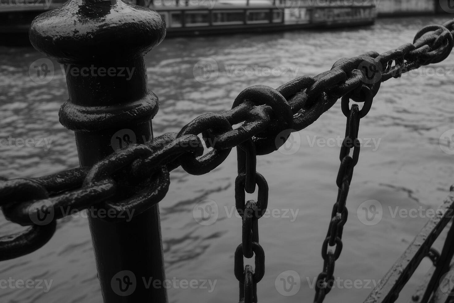 Close-up of a chain linked to a railing by the water. photo