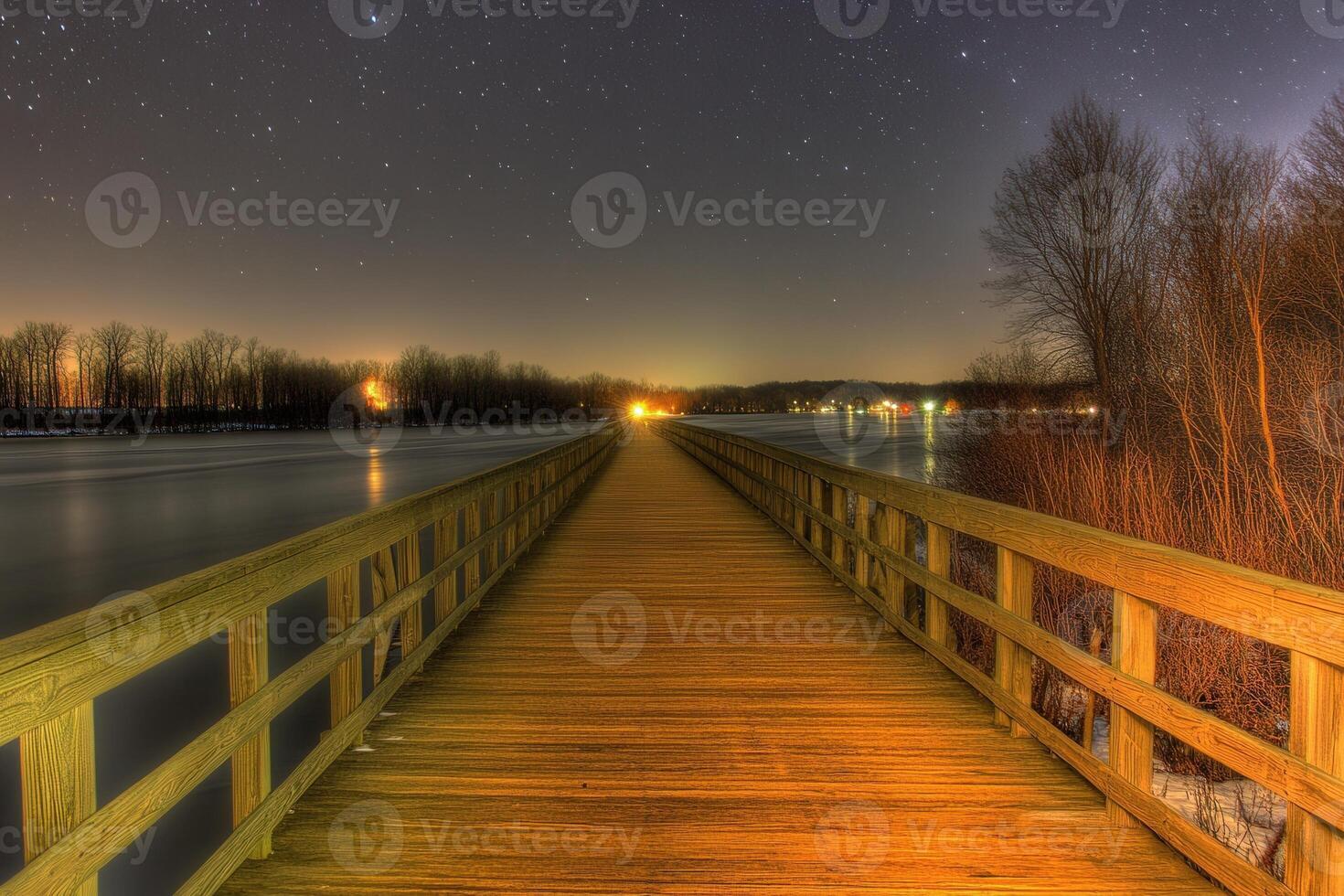 Night view of a wooden pier extending over water. photo