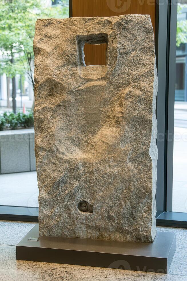 Large, light-gray stone block with a square hole photo