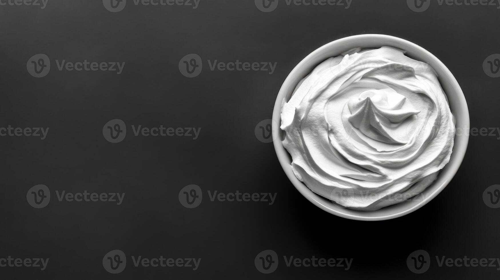Bowl of whipped cream on dark background, simple dessert photo