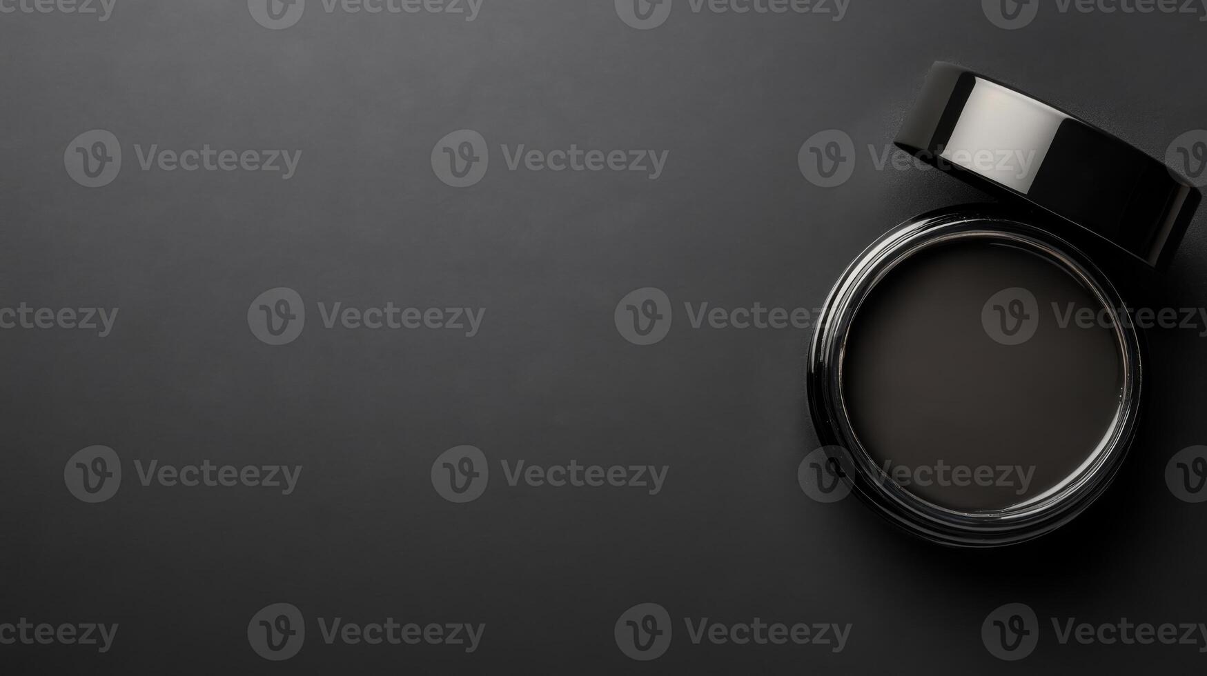 A sleek black container with a glossy lid on a minimalist dark surface photo