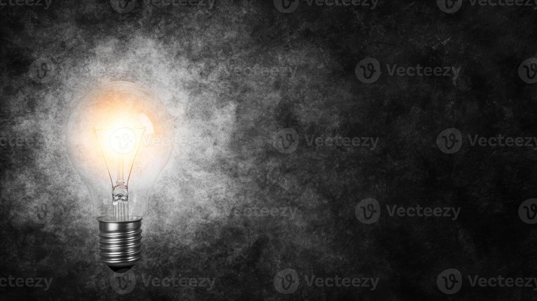 A glowing light bulb illuminating the darkness on a textured background photo