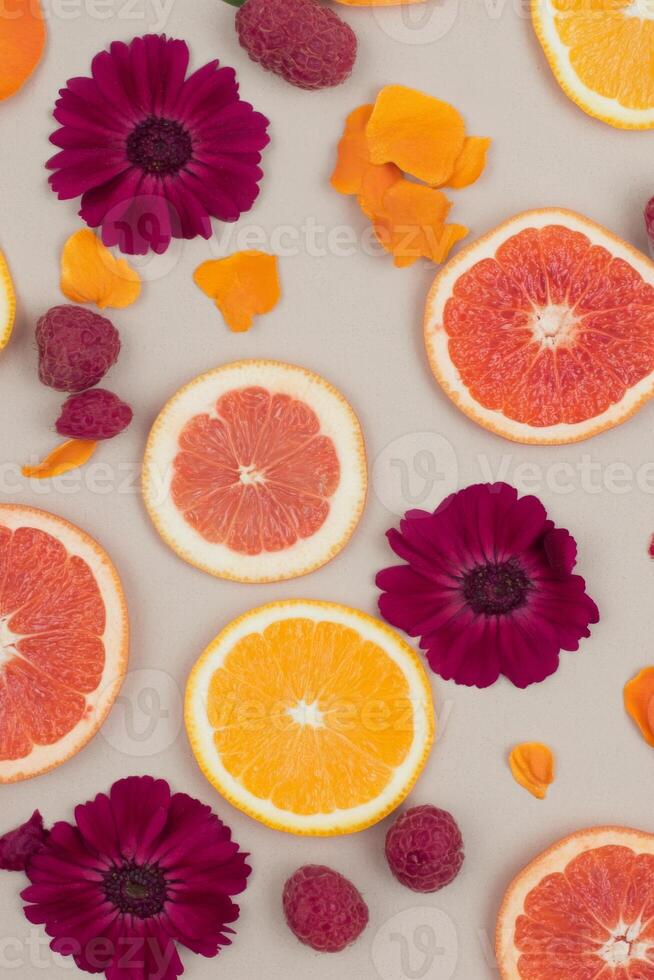 Vibrant Citrus Slices and Deep Red Flowers Create a Colorful Pattern photo