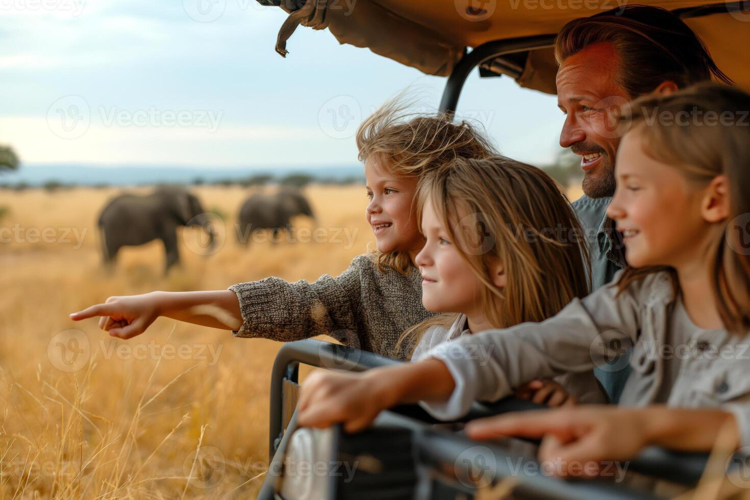 A joyful father and his three daughters explore wildlife, pointing excitedly at elephants in the distance. photo