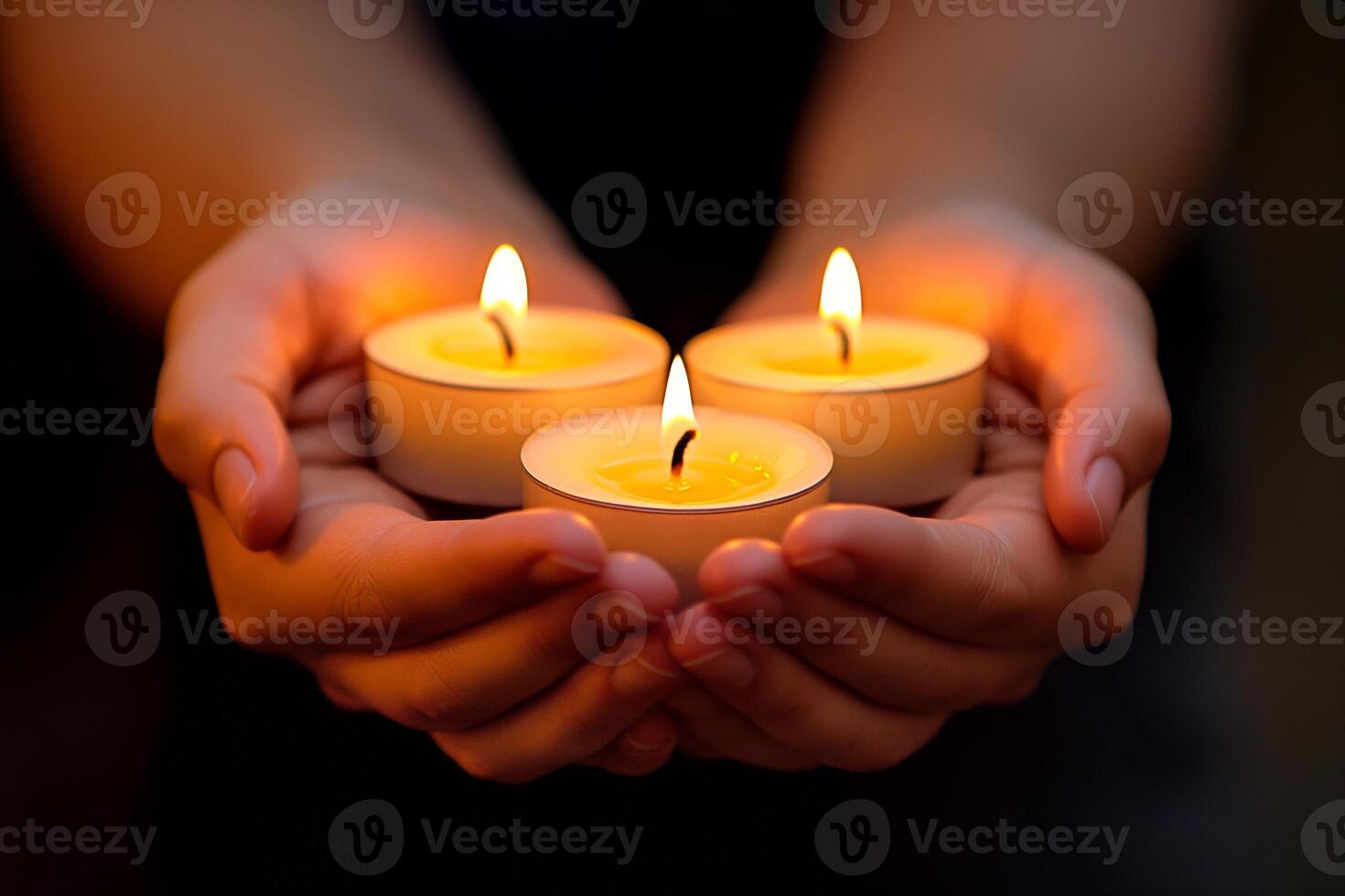 A close-up of a pair of hands, holding three flickering candles, creating a warm and serene atmosphere. photo