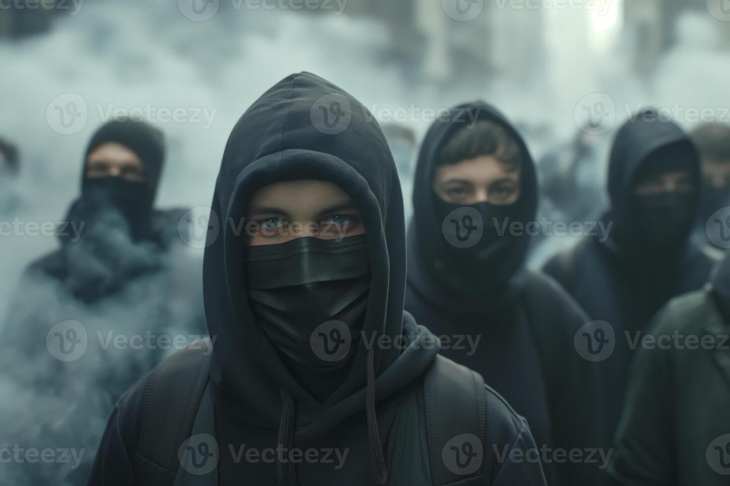 A group of young individuals in dark hoodies and masks, standing resiliently amidst a misty urban backdrop. photo