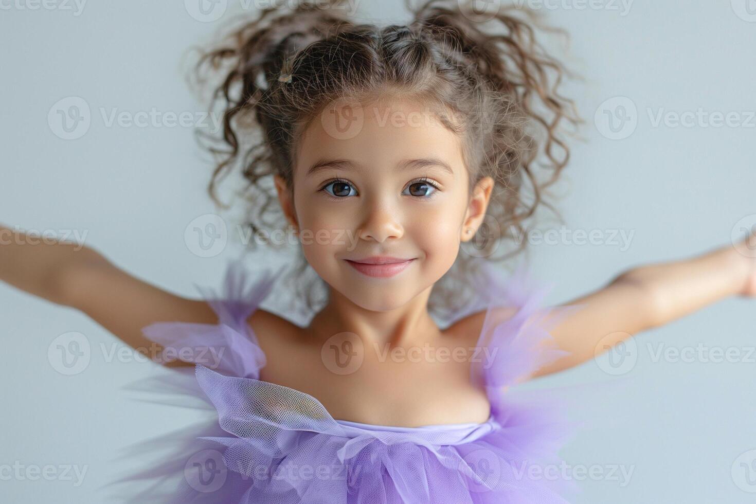 A joyful Hispanic girl in a purple tutu poses with arms wide open, expressing happiness and innocence. photo