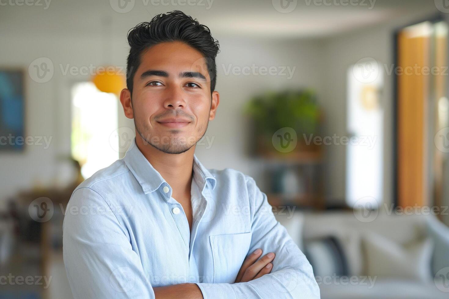 Smiling Hispanic man in a light blue shirt, exuding confidence in a bright, modern living space. photo