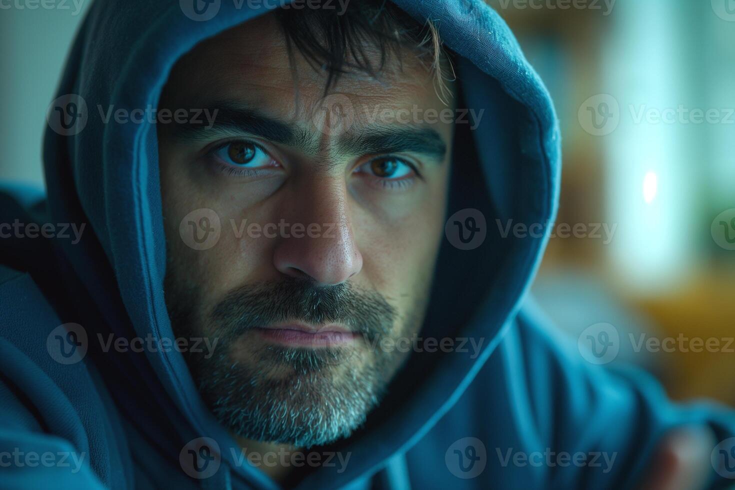 Focused middle-aged man in a hoodie gazes intently with a serious expression. photo