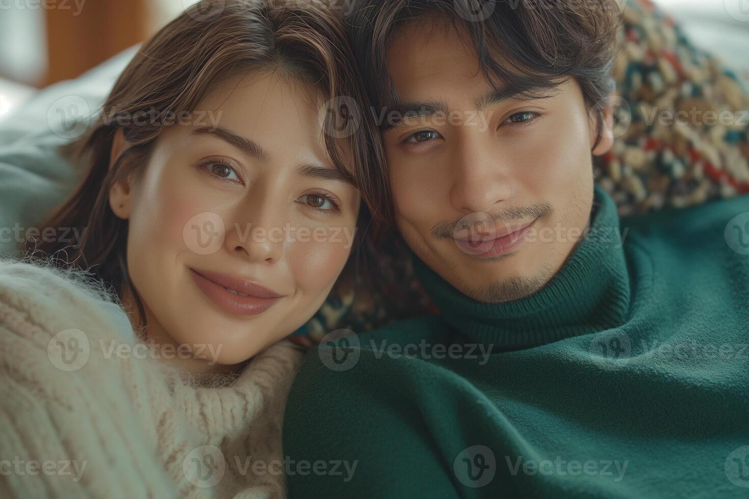 A close-up of a young Asian couple cuddling on a couch, radiating warmth and affection. photo