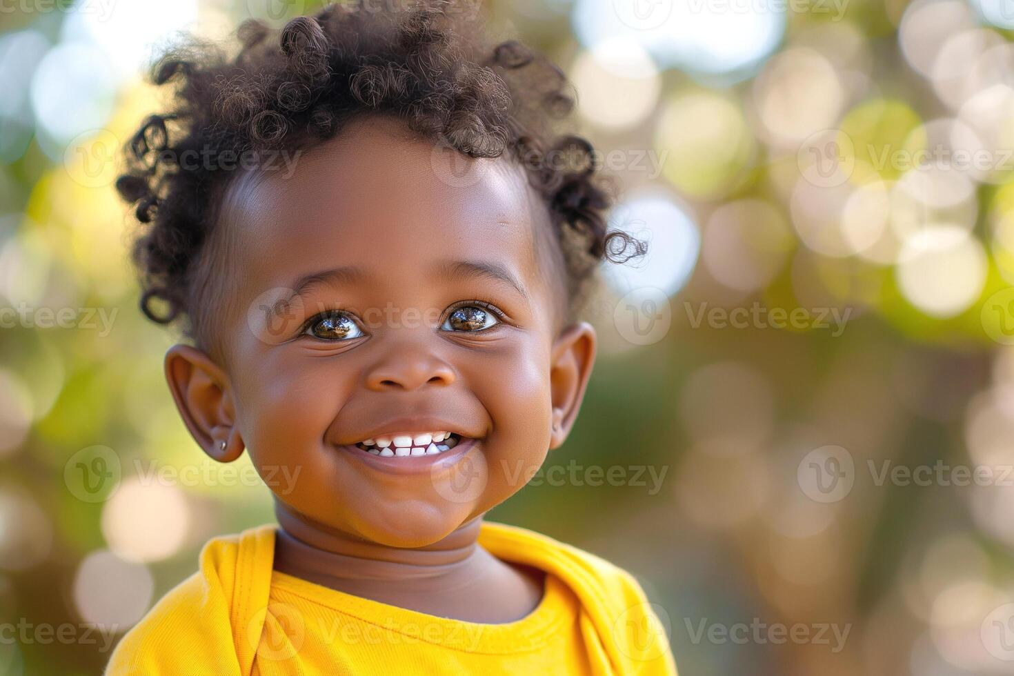 A joyful Black baby with curly hair smiles brightly, showcasing an infectious happiness in a sunlit outdoor setting. photo