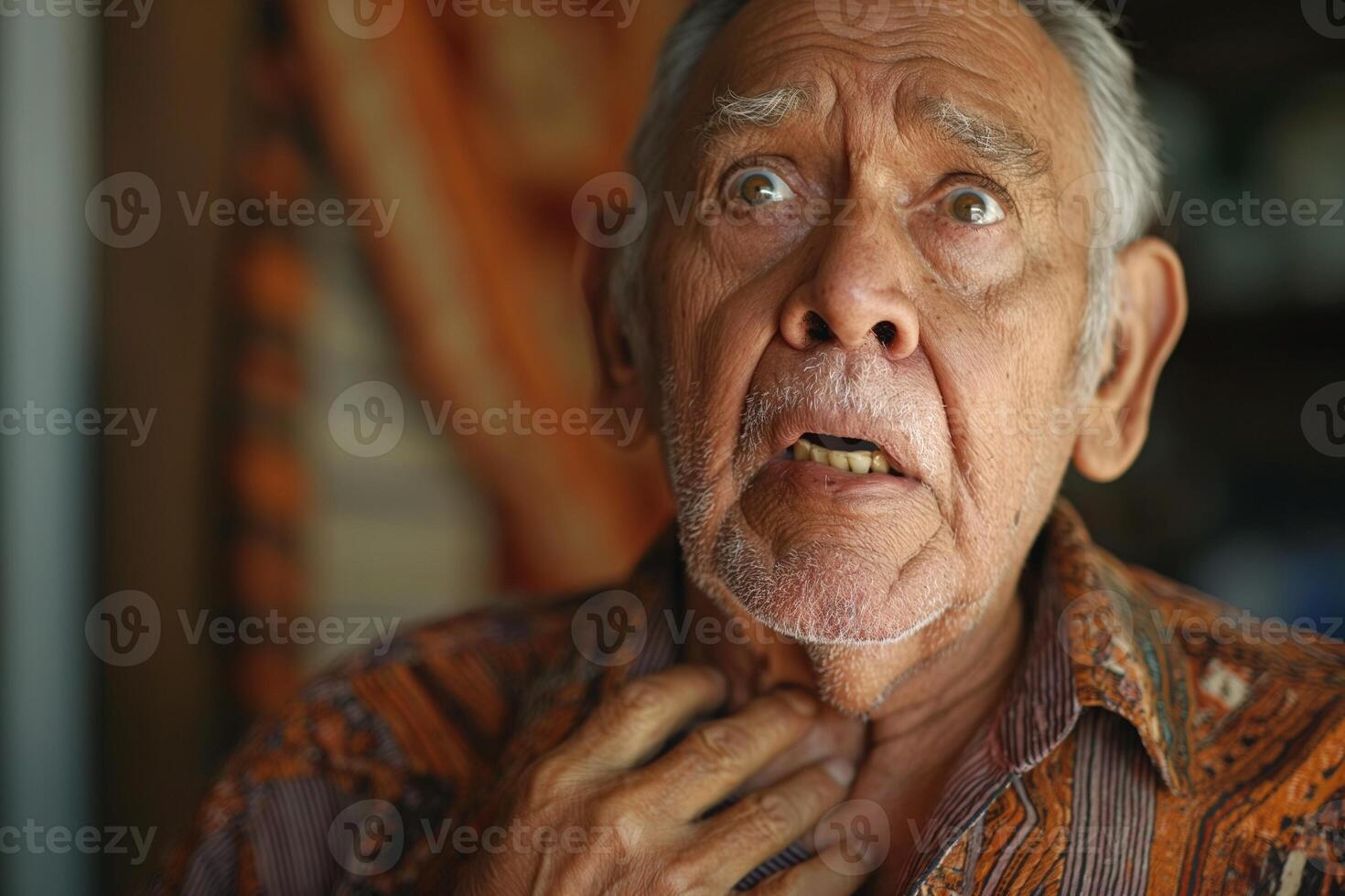 An elderly Hispanic man appears shocked and distressed, showcasing deep wrinkles and a concerned expression in his home environment. photo