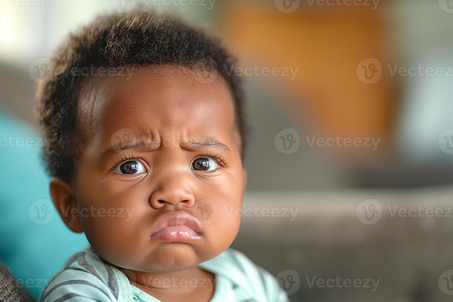 A curious African American baby with big brown eyes and a furrowed brow, sitting on a cozy sofa. photo