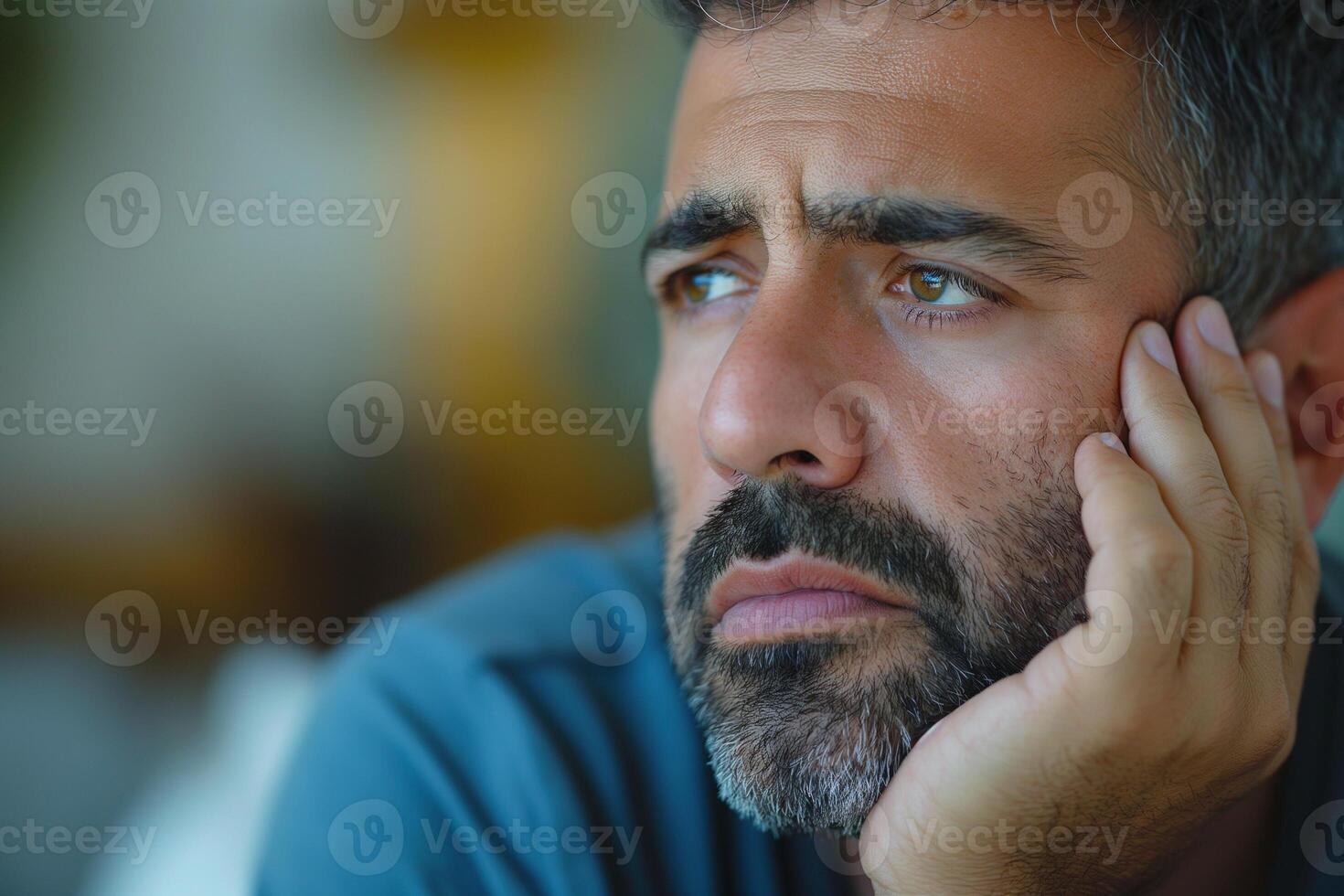 A contemplative middle-aged man with a beard, lost in thought and gazing off into the distance. photo