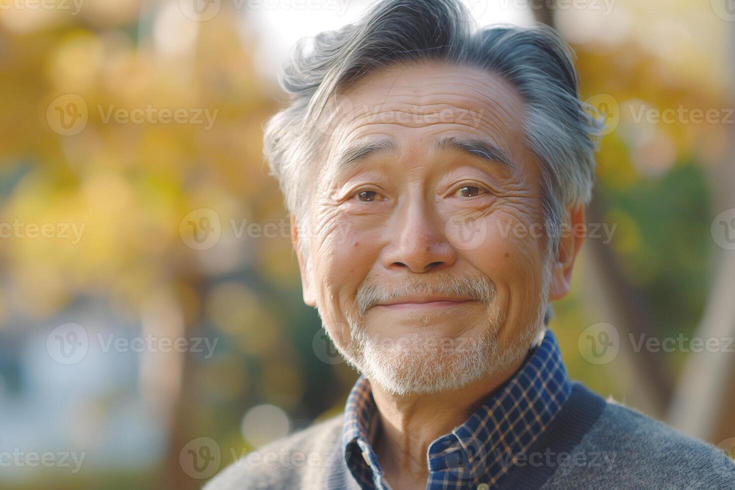 Smiling elderly Asian man in a sweater, exuding warmth and joy against a backdrop of autumn foliage. photo