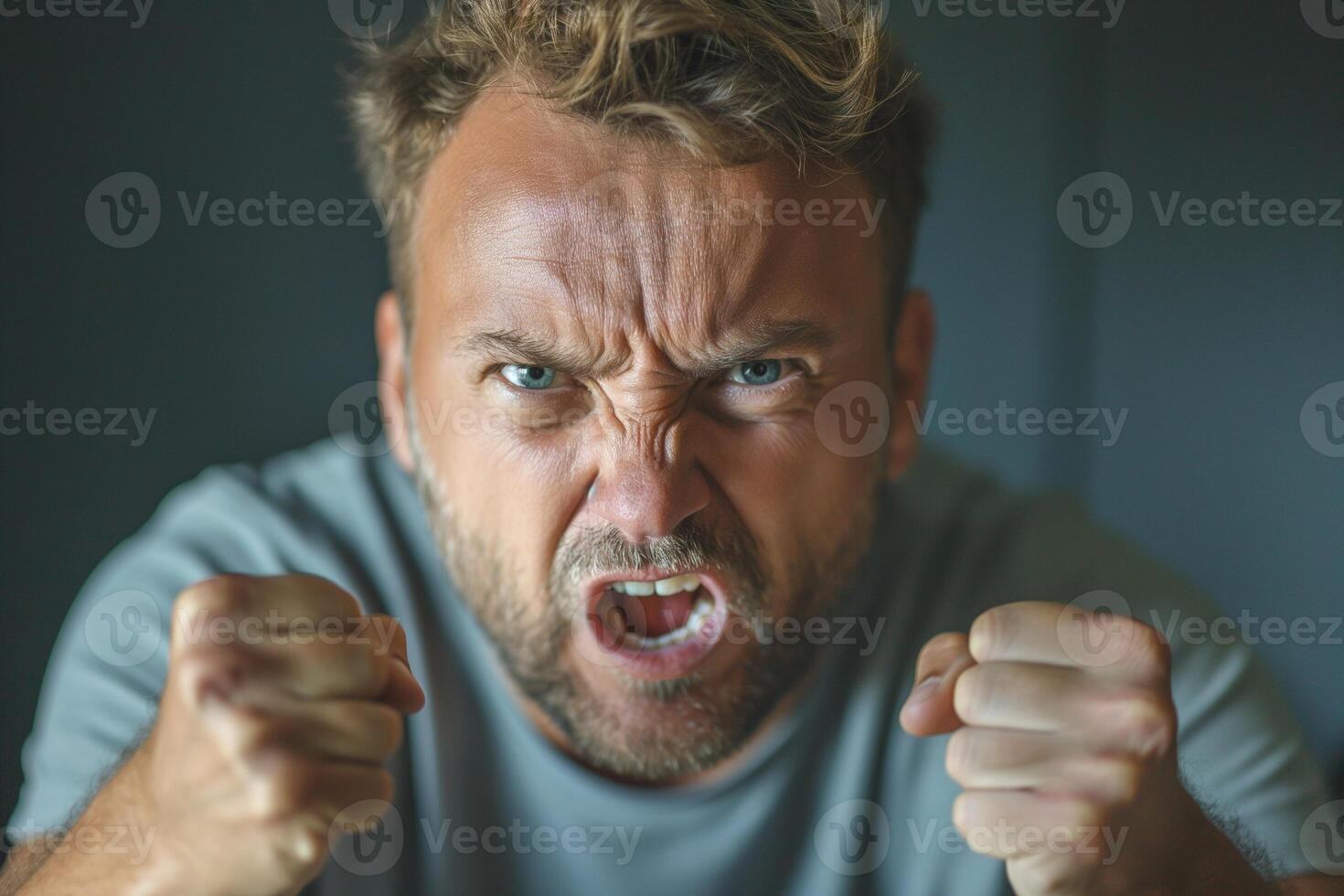 Angry Caucasian man expressing intense frustration with clenched fists and a fierce glare. photo