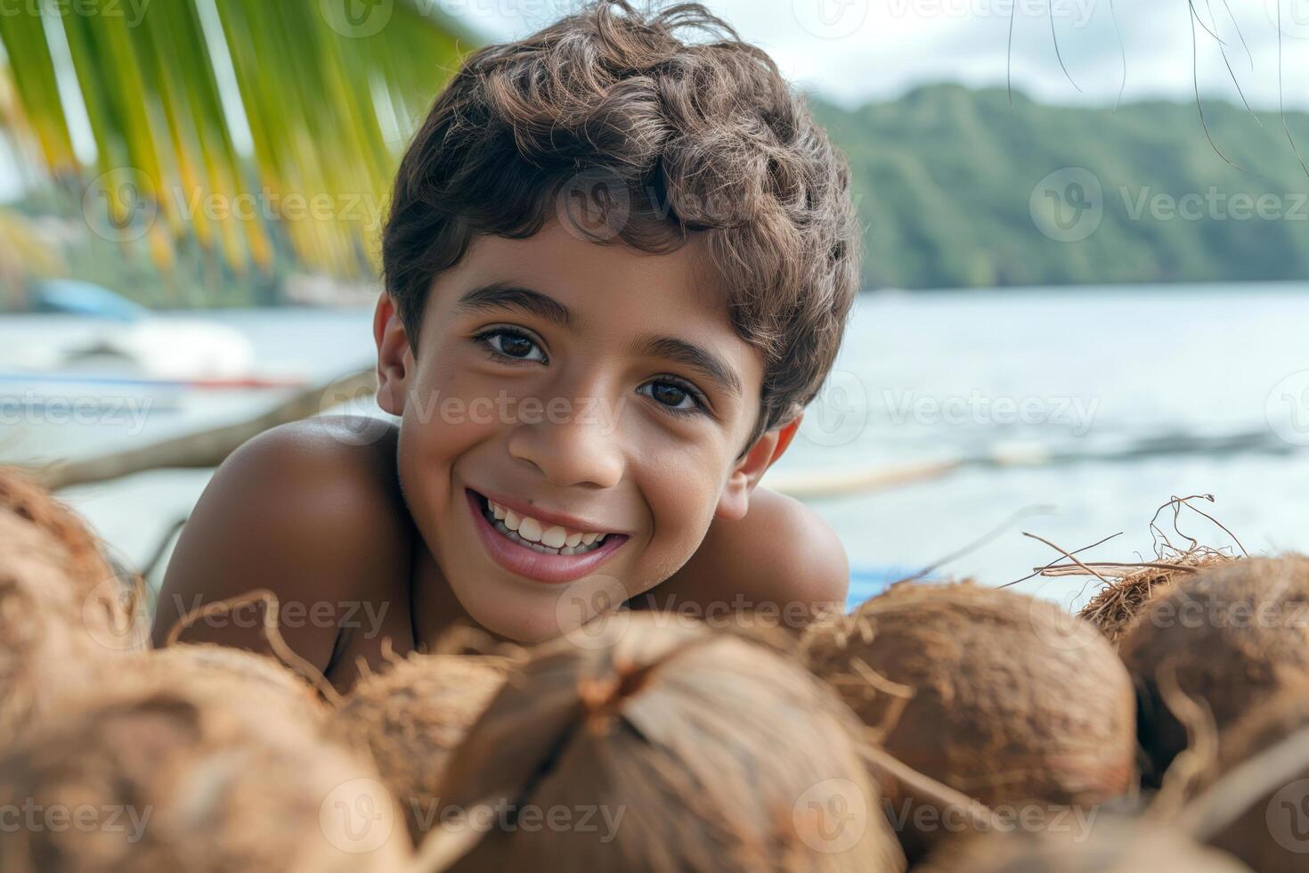 Cheerful young boy, of Middle Eastern descent, smiling playfully among coconuts on a tropical beach. photo