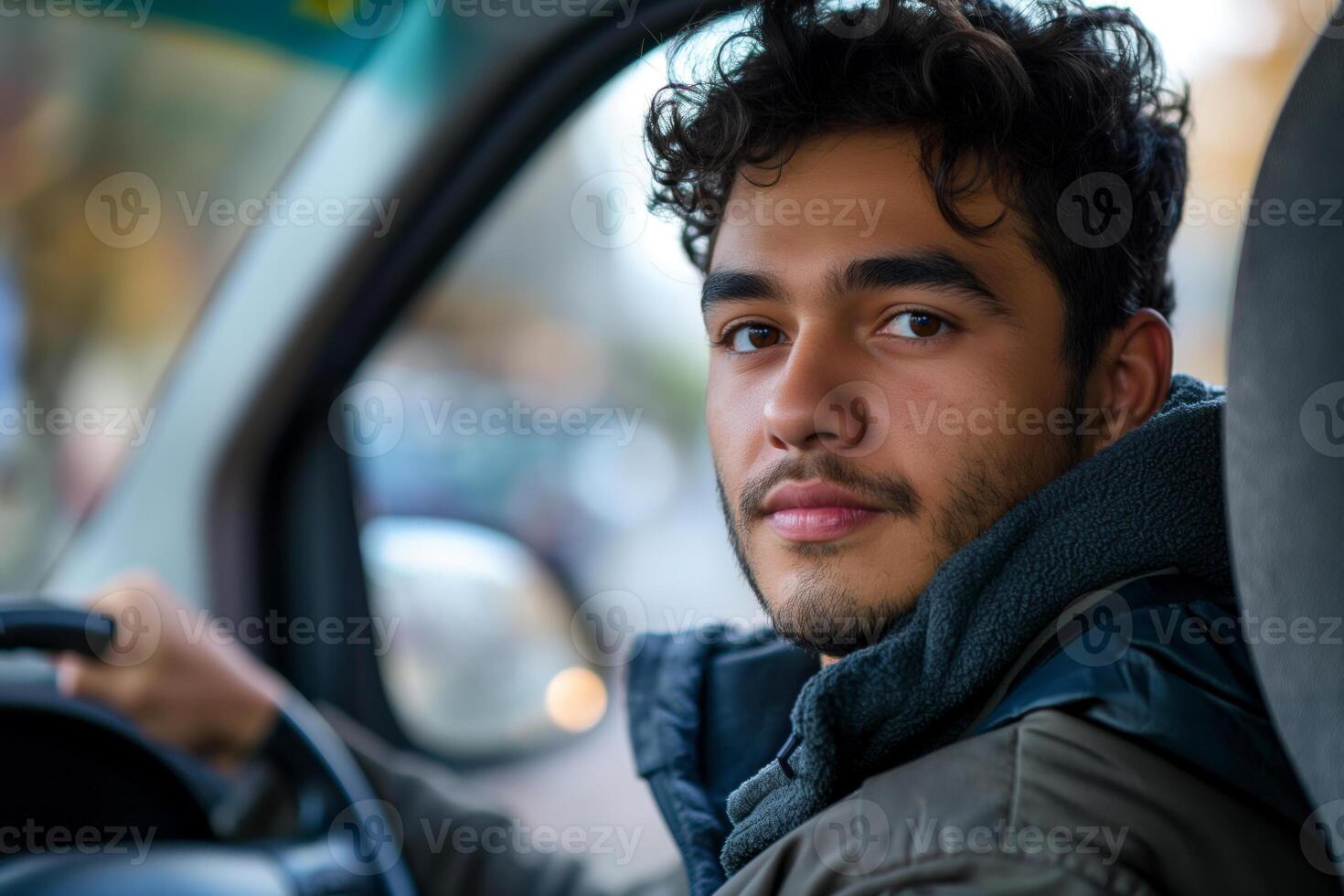 A young Hispanic man with curly hair, looking thoughtfully out of a vehicle window, wearing a cozy jacket. photo