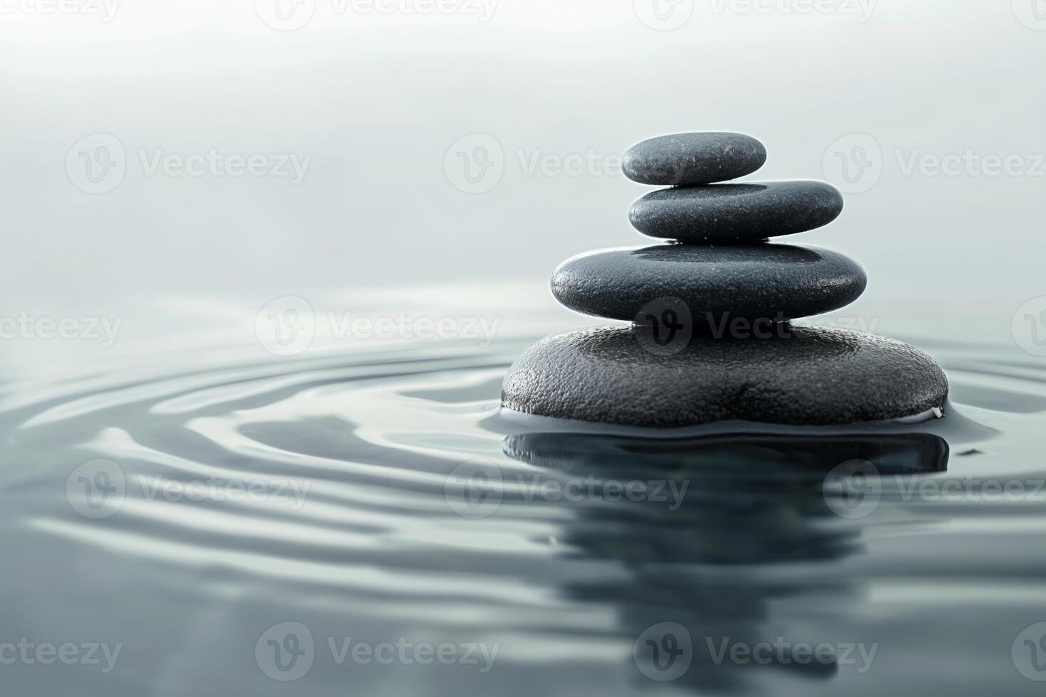 A serene stack of smooth black stones balanced on the surface of gently rippling water, creating a peaceful atmosphere. photo