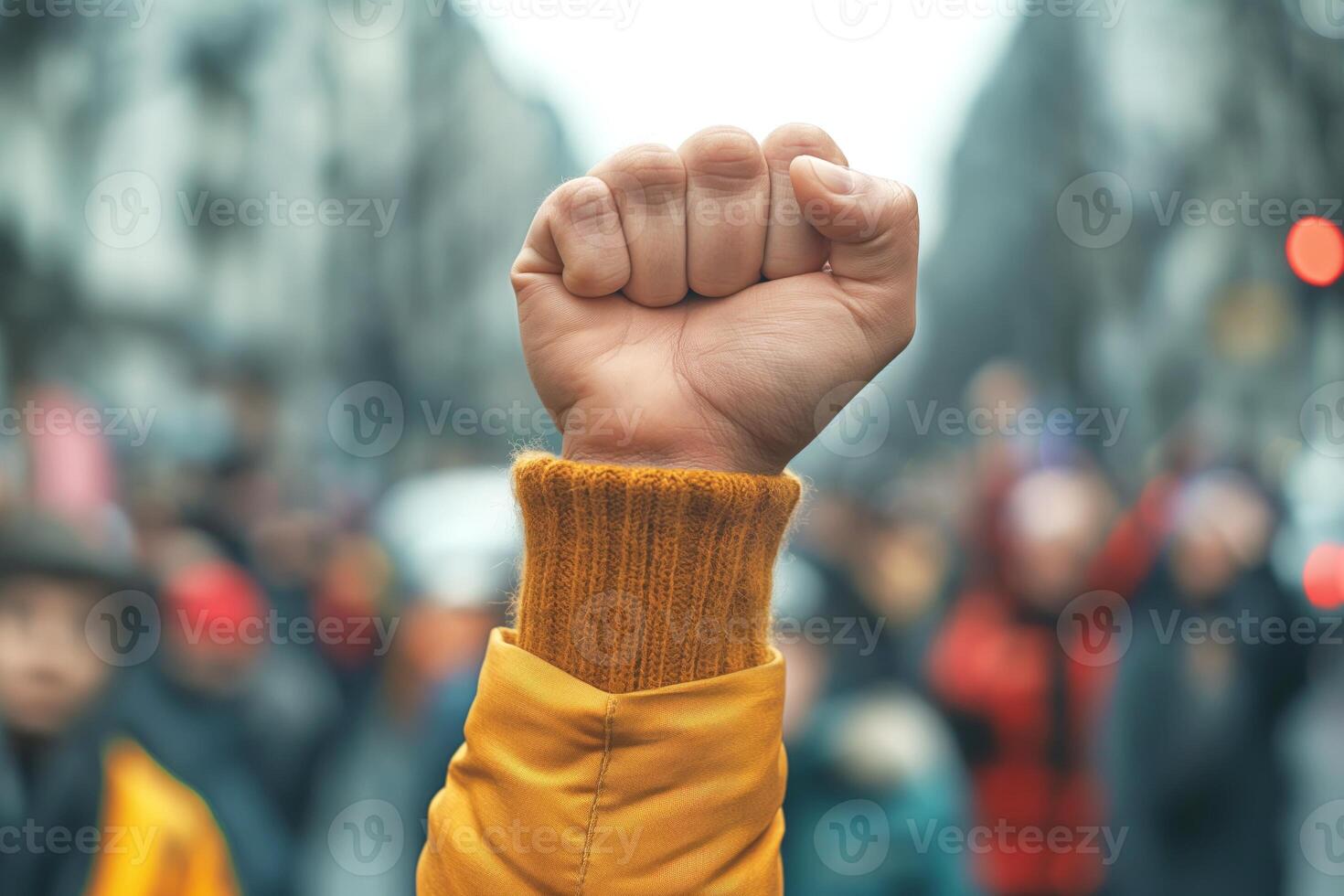 A raised fist of a young person in a yellow sweater symbolizes unity and resilience during a demonstration. photo