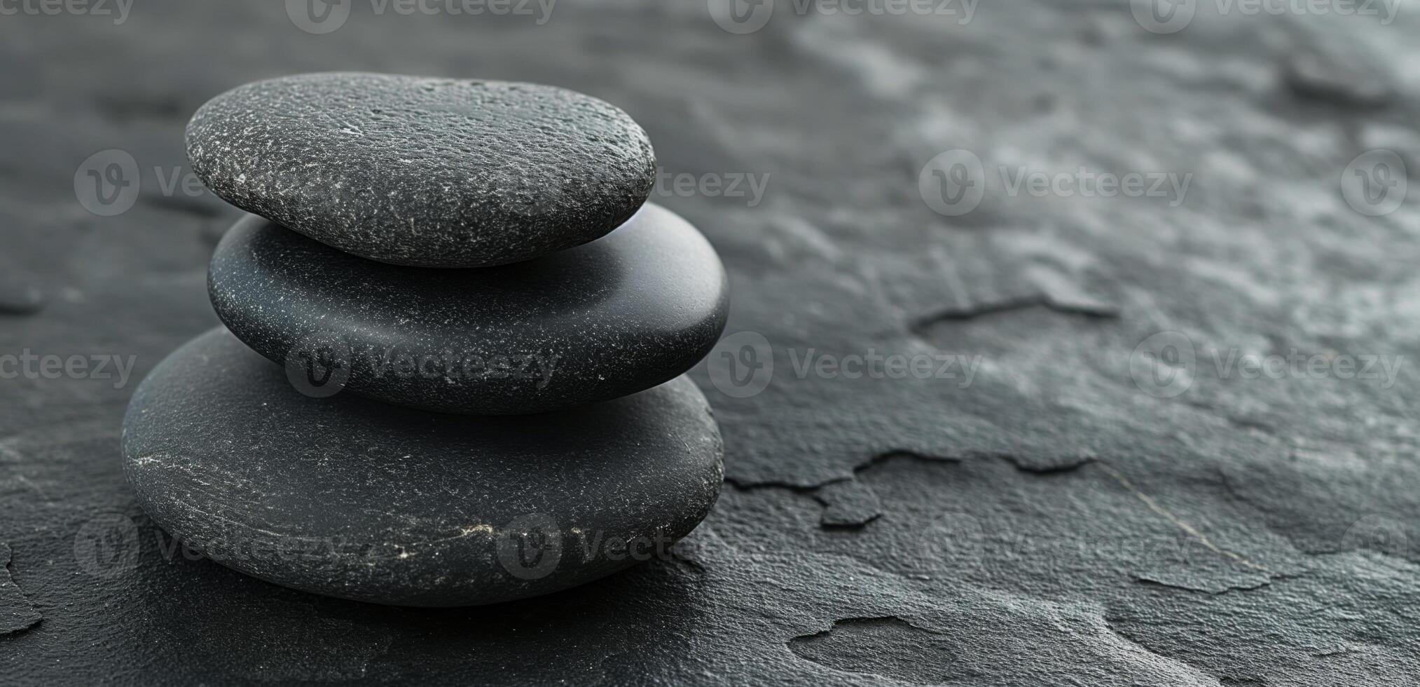 Three stacked black stones on a textured dark surface, symbolizing balance and tranquility. photo