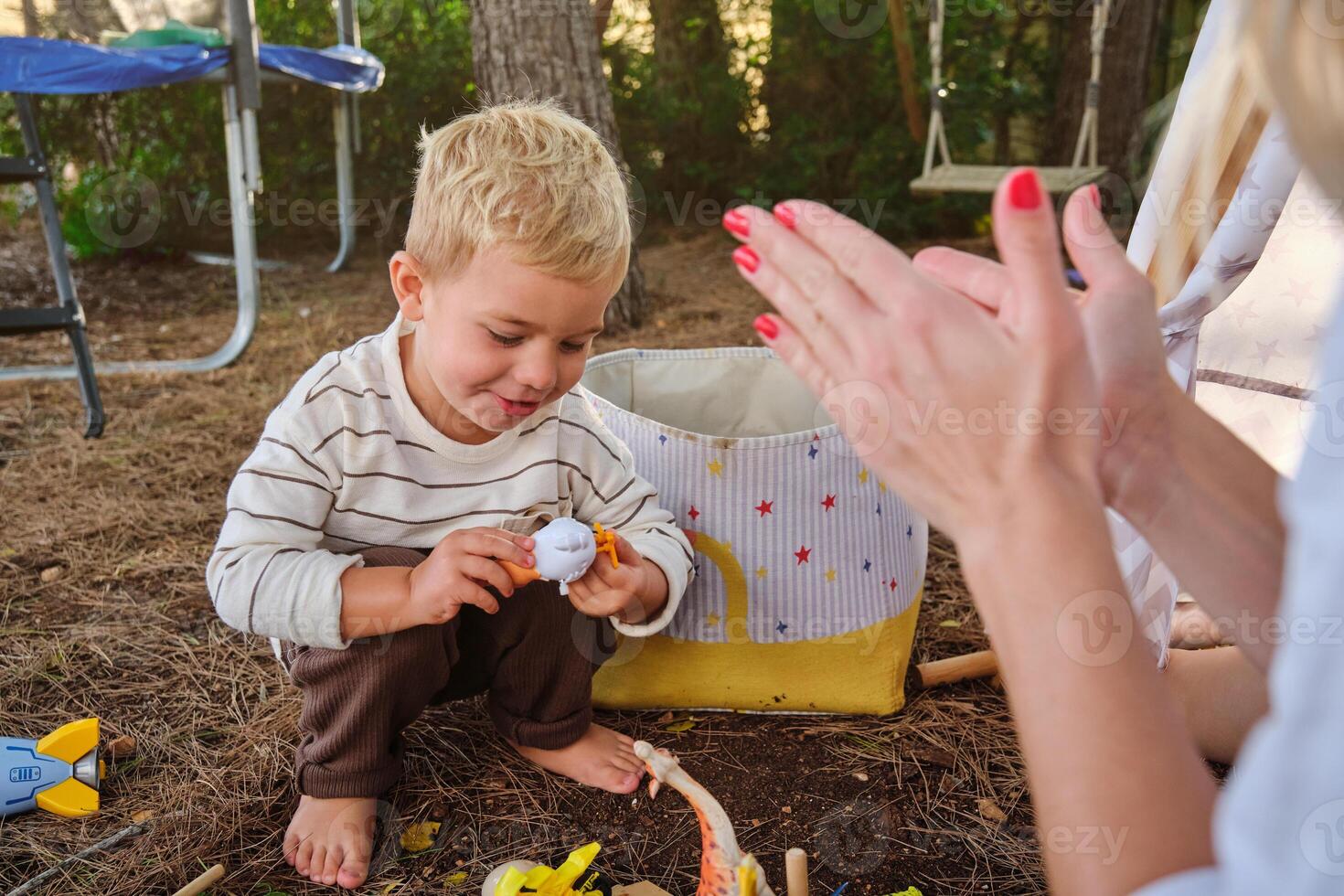Mother applauding son playing with toy photo