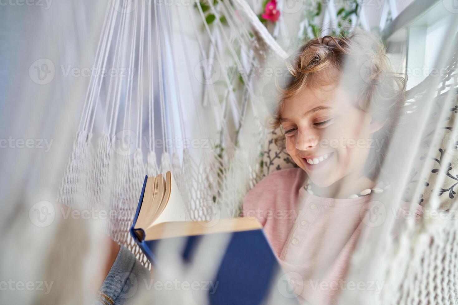 Cheerful kid with book in hammock photo