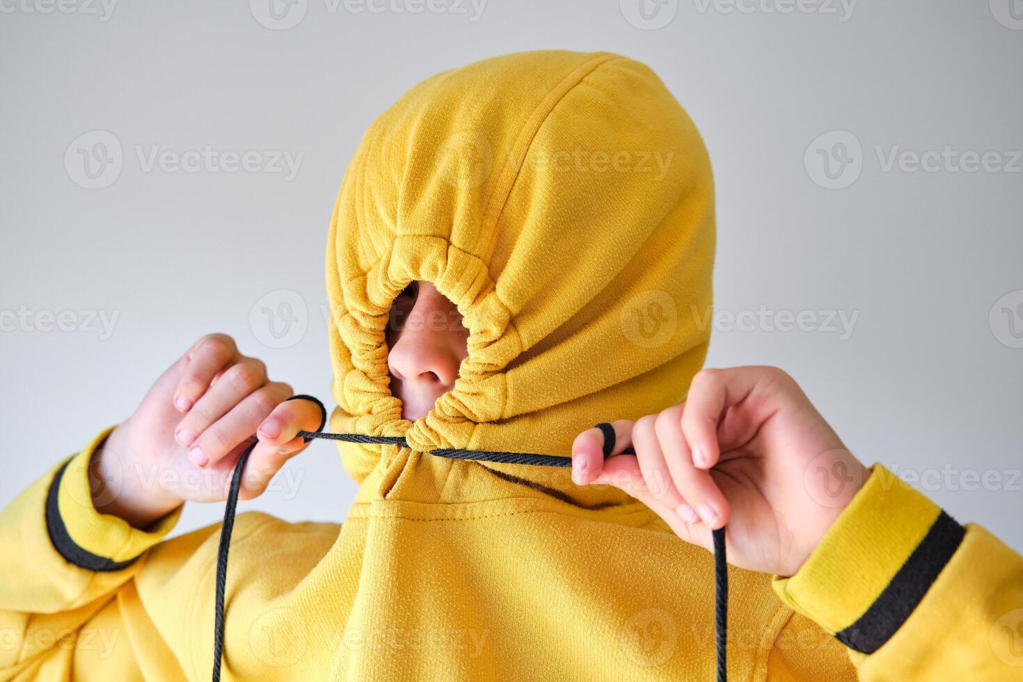 Anonymous child tightening drawstrings on hood photo