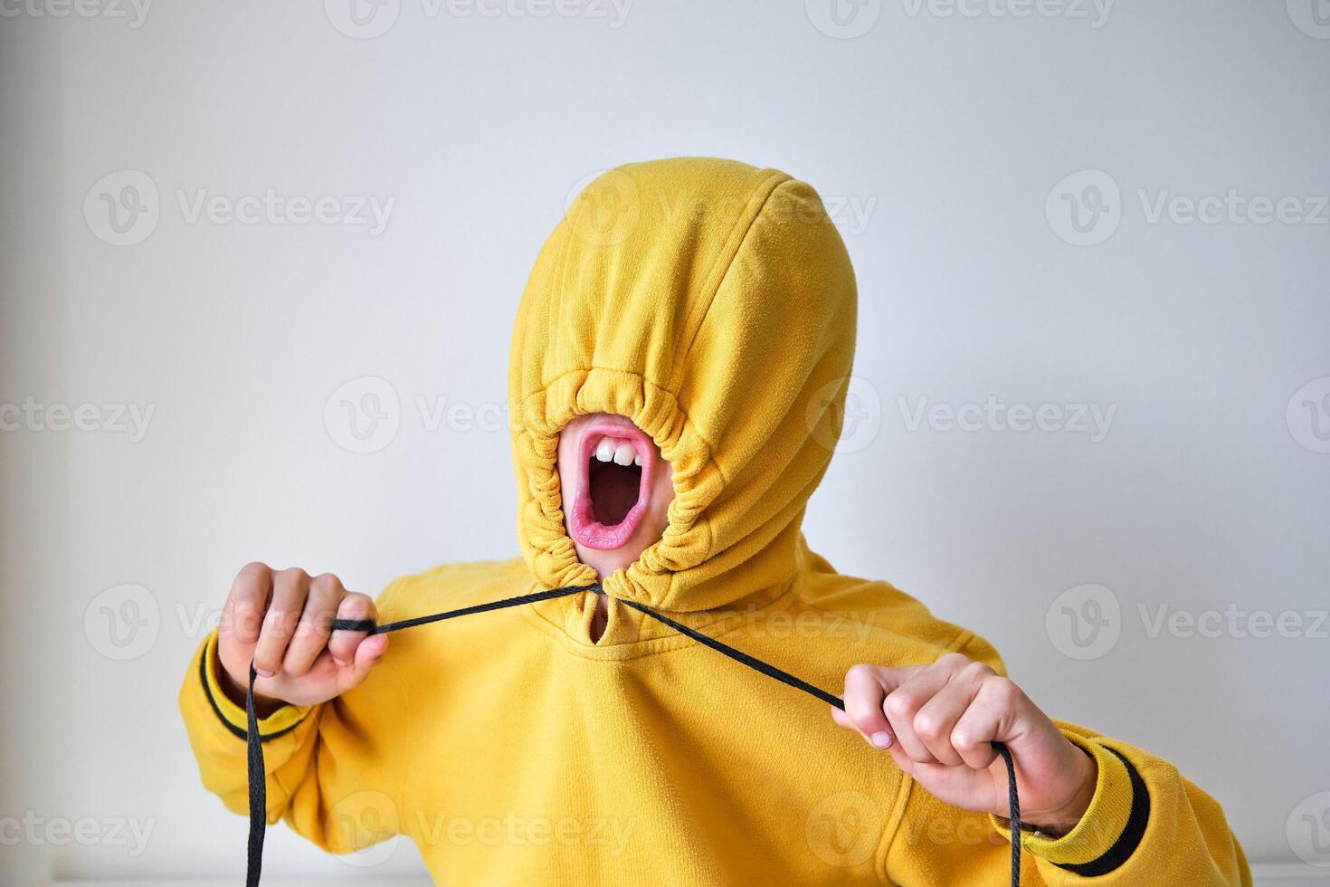 Unrecognizable kid yelling while tightening hood on head in stud photo