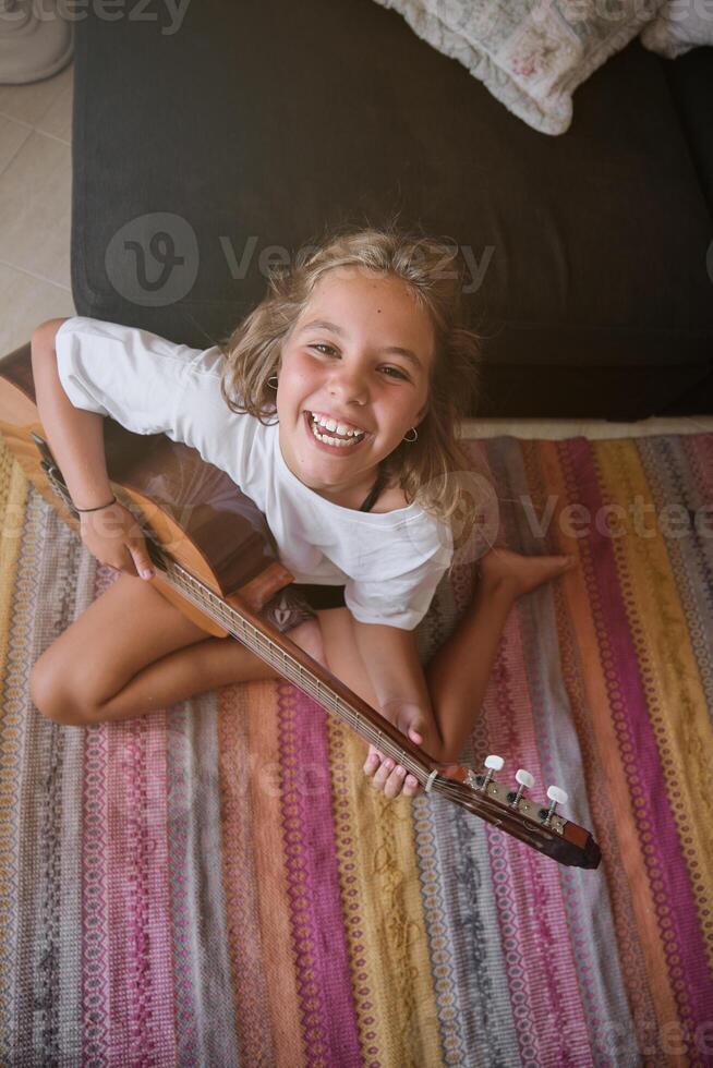 Lovely innocent girl playing acoustic guitar on floor photo