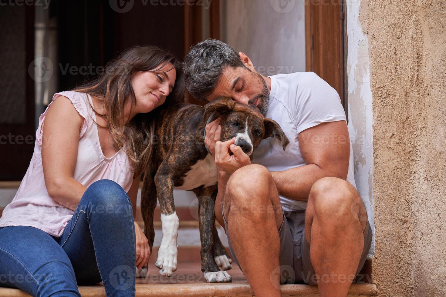 Happy couple petting dog on porch photo
