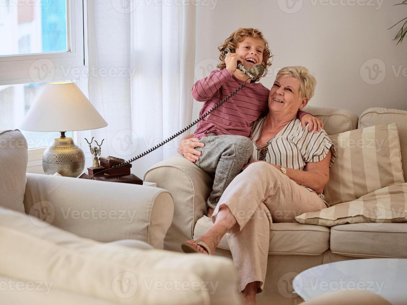 Laughing boy answering telephone call while resting with aged gr photo