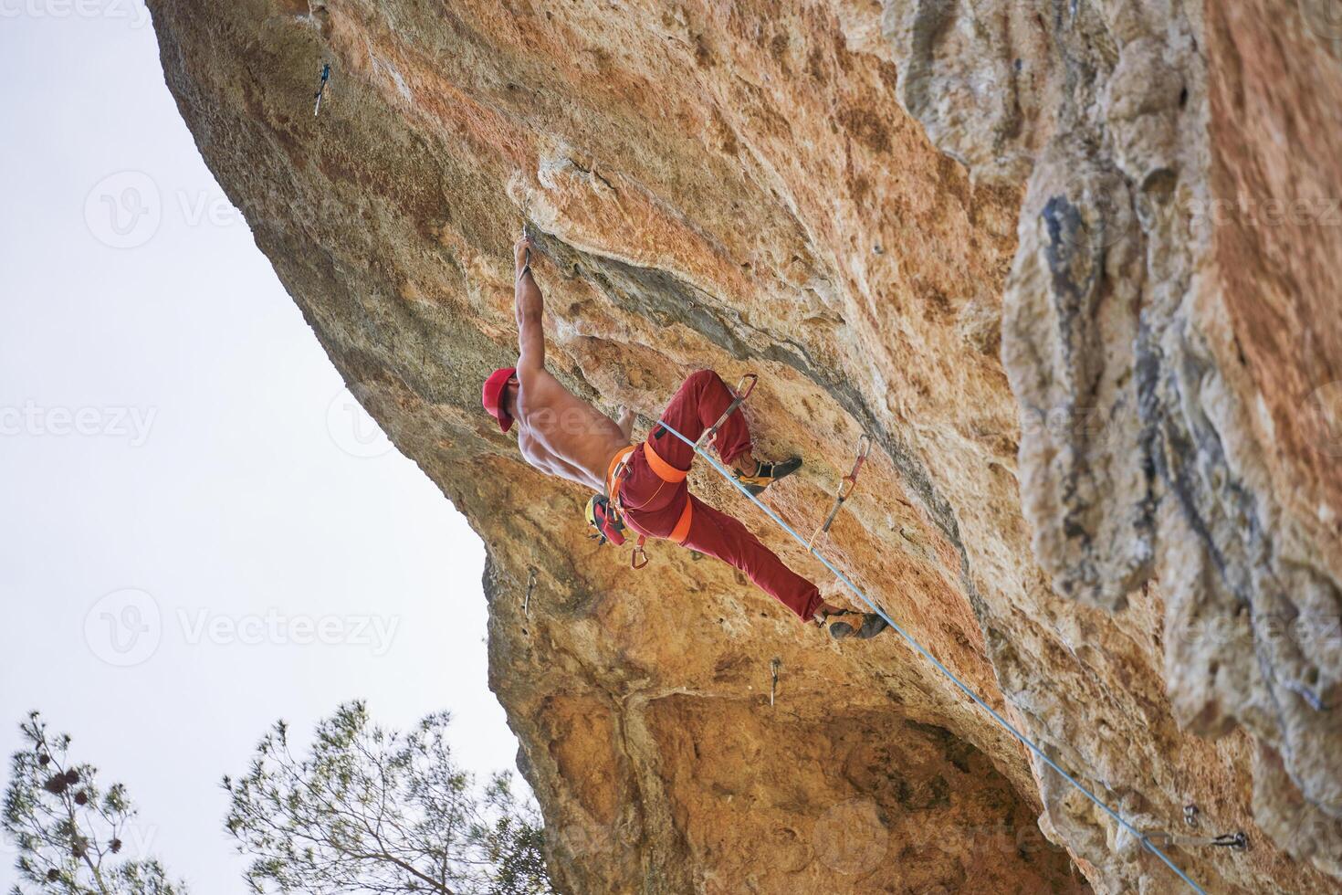 Faceless strong climber holding onto rock while hanging on rope photo