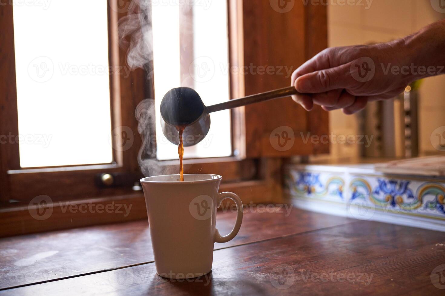Unrecognizable person pouring coffee into mug photo
