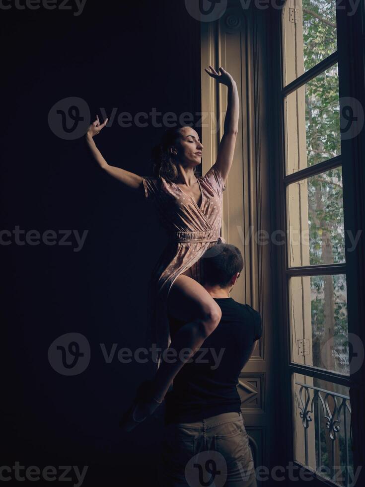 Ballerina on shoulder of faceless dancer near window photo
