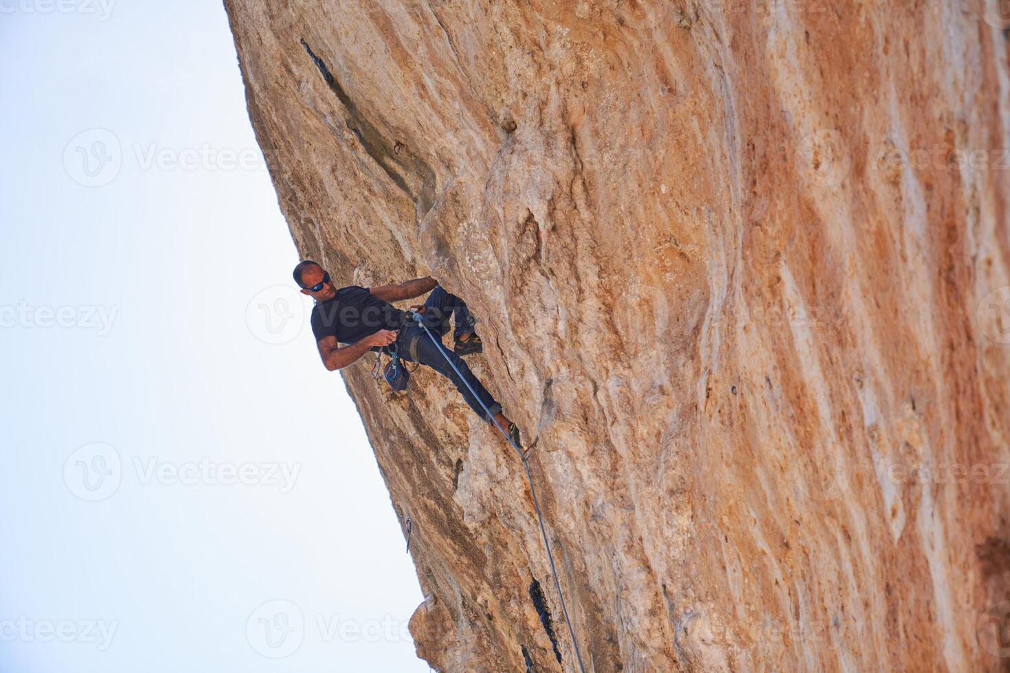 Strong climber climbing rocky mountain slope photo