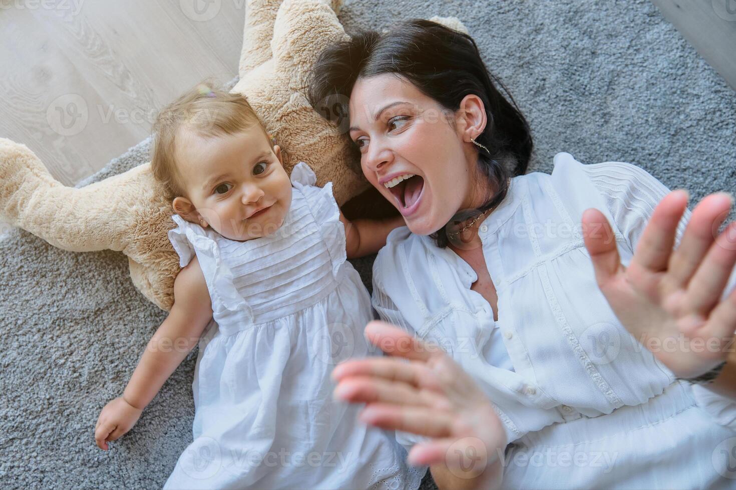 Cheerful mother and daughter lying on carpet photo