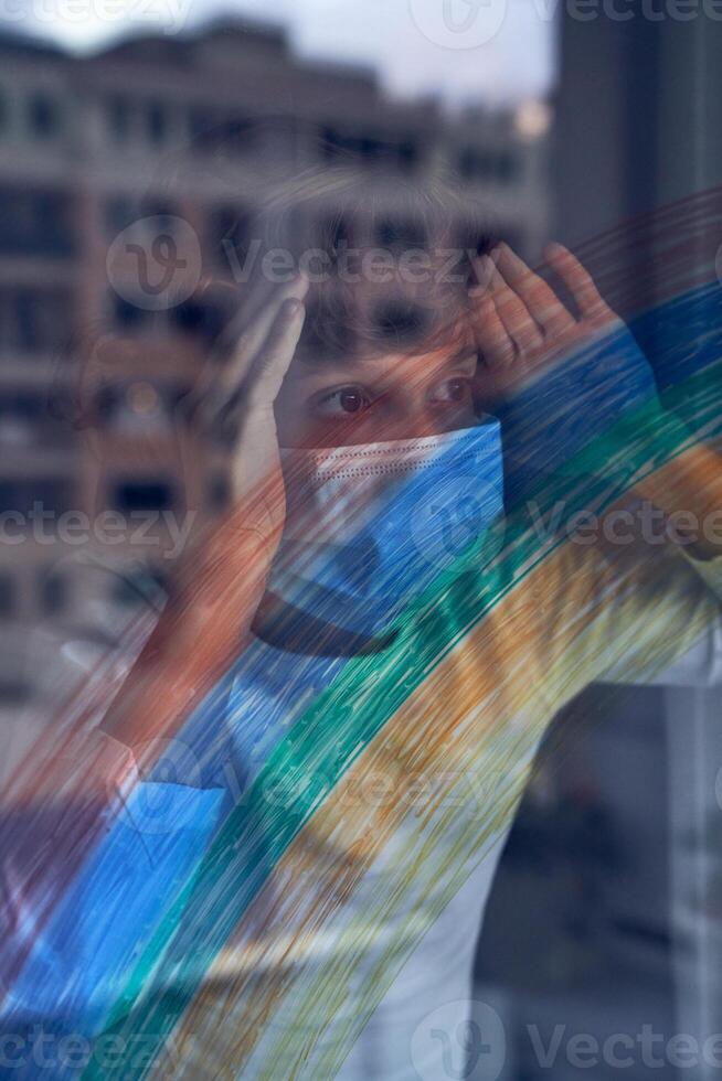 Child in mask looking through window at home photo