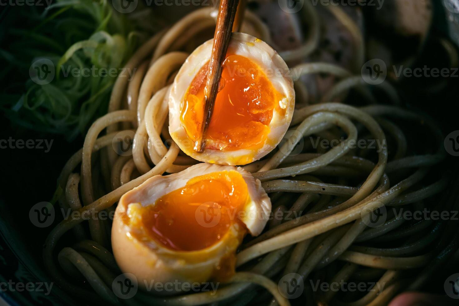 Halves of soft boiled egg on noodles photo